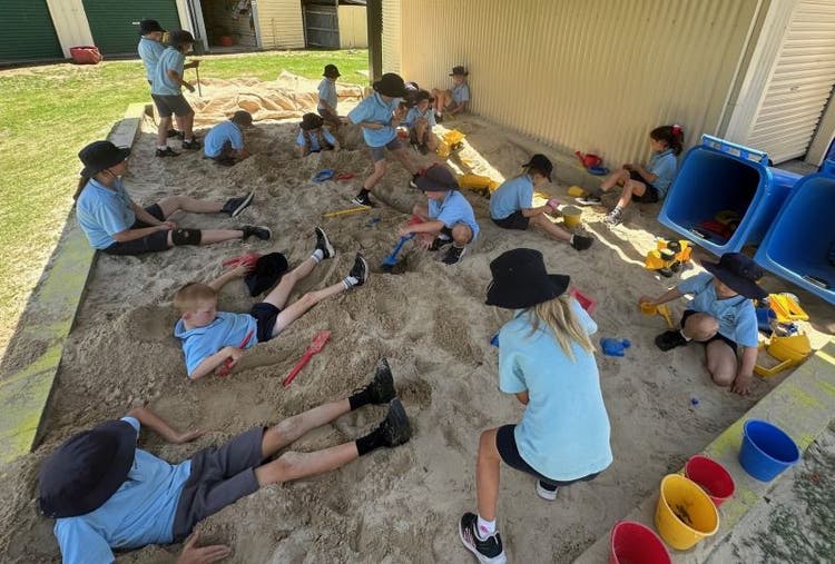 Boys and girls playing in a shaded sandpit